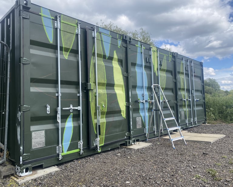 Three-quarter view of shipping container with painted colours filling taped leaf shapes