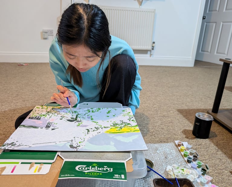 lady in blue dress sitting and painting carefully