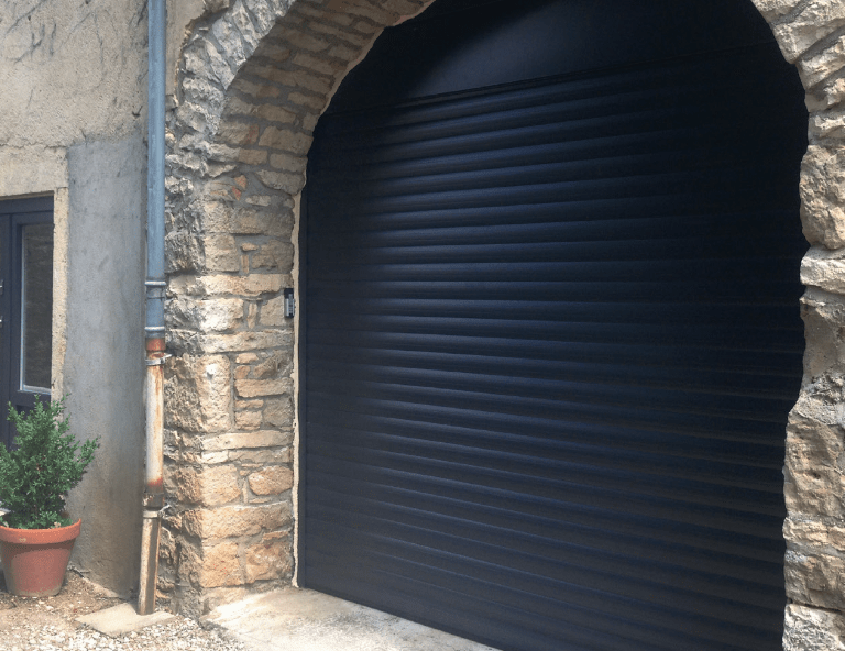 Porte de garage enroulante gris anthracite RAL 7016 installée sur façade en pierre par LB Menuiserie