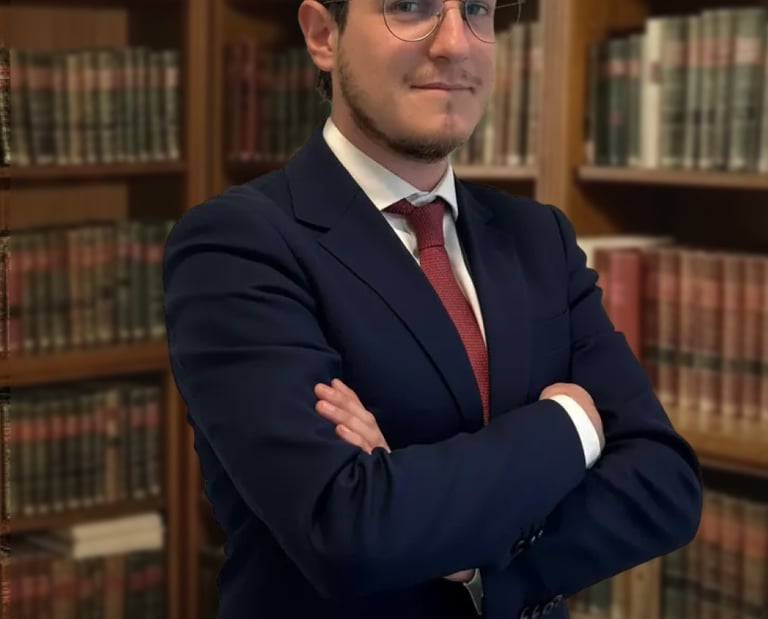 Professional male attorney in a navy suit standing with arms crossed in a legal library.