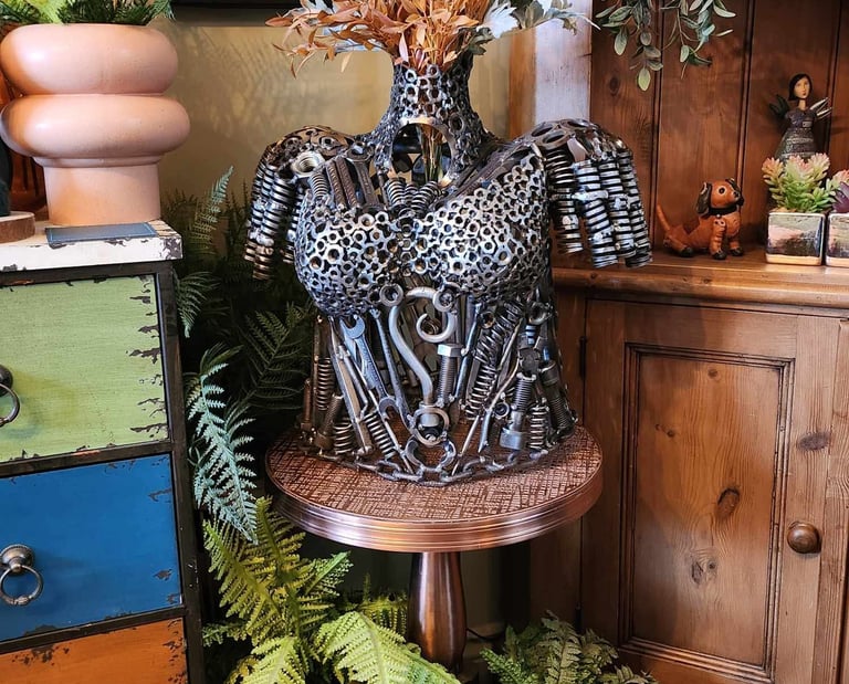 steampunk female torso lifesize bust sculpture made from metal nuts bolts and tools in a rustic room