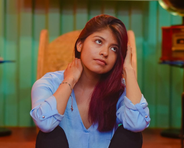 A pensive young woman with auburn hair sits in a vintage room with a gramophone.