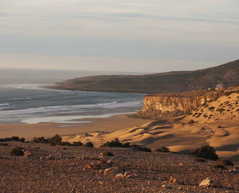 Plage magnifique au coucher de soleil avec l'océan, des dunes de sable et des falaises