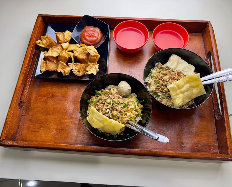 Tray berisi dua mangkuk mie ayam dengan topping lengkap, dua mangkuk saus, dan pangsit goreng