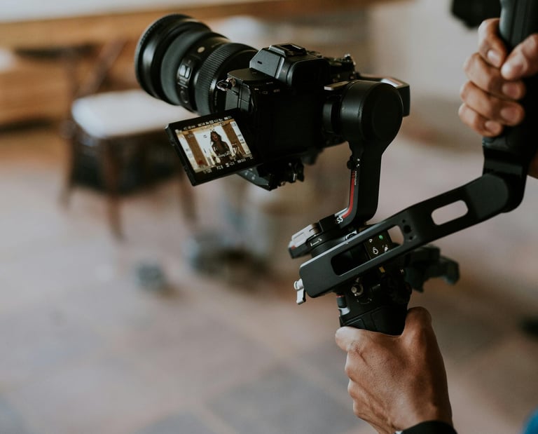 Professional videographer holding a mirrorless camera on a 3-axis gimbal stabilizer for smooth video production.