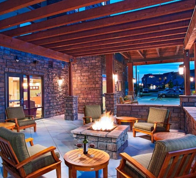 a patio with a fire pit and chairs