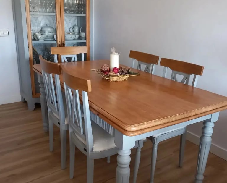 una mesa color madera y cinco sillas color gris con una vitrina de fondo del mismo color