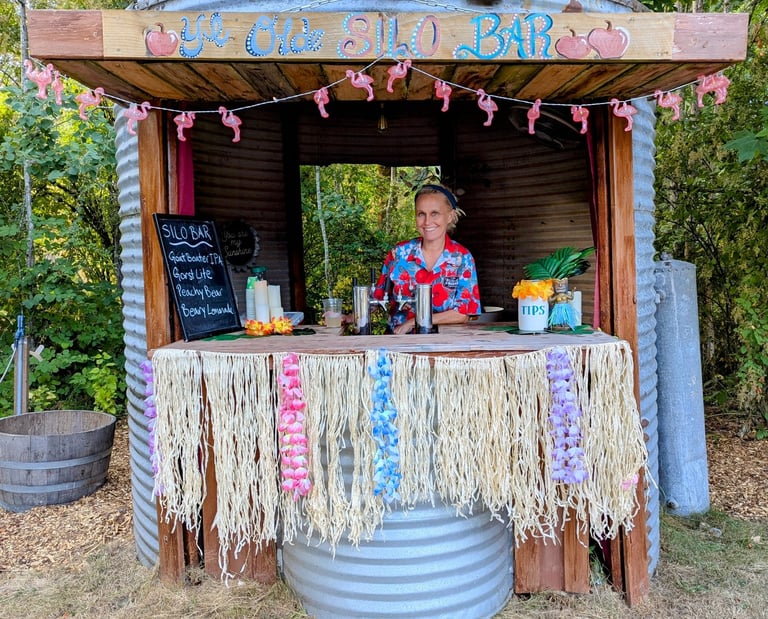 A woman serves drinks at a tropical-themed tiki bar built inside a repurposed metal grain silo.