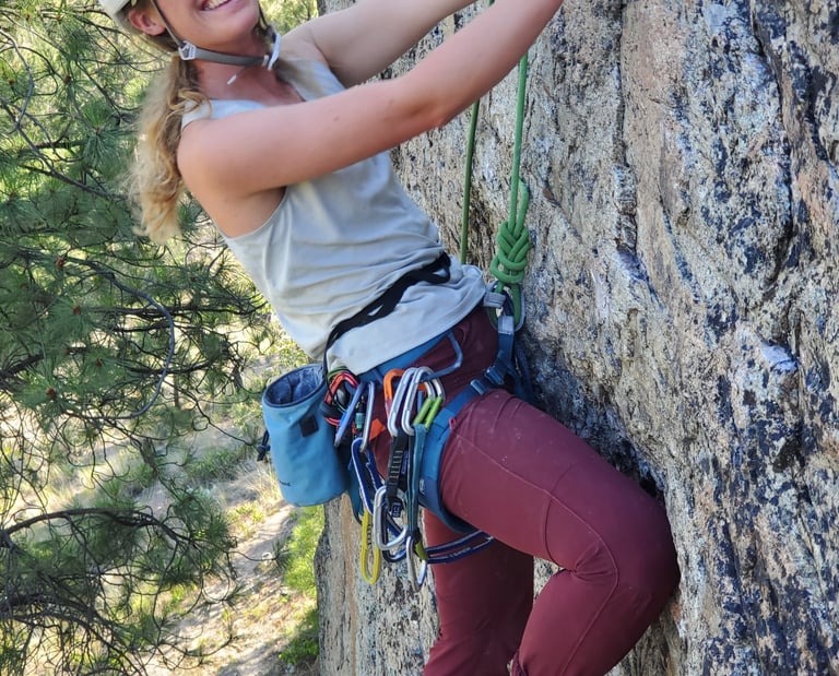 A smiling woman climbing an outdoor rock face