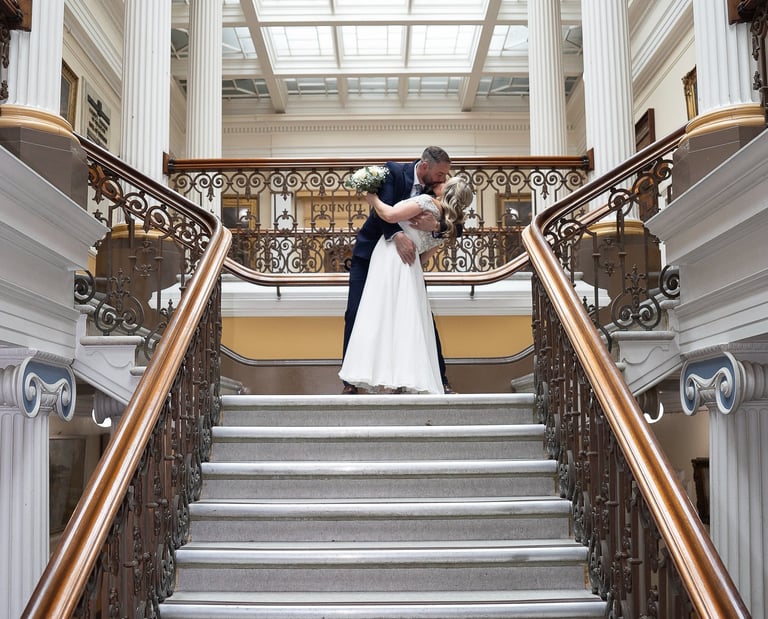 Bride and groom kissing on grand staircase wedding venue, Brighton UK