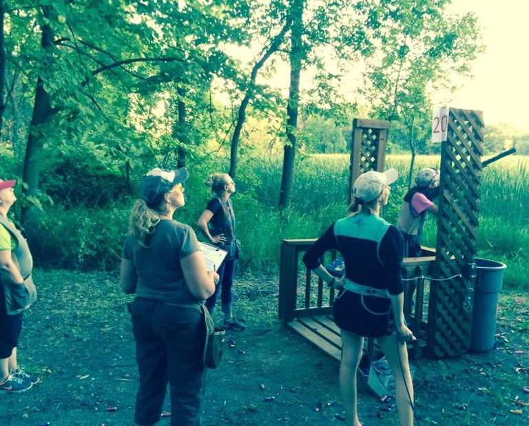 Group of women watching teammate shoot on a sporting clays station.