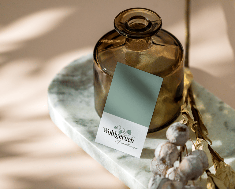 Eine Visitenkarte für Aromatherapie, die an einer braunen Glasflasche lehnt.