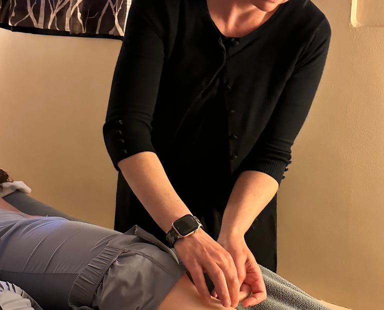 Acupuncturist inserting needle into patient’s lower leg on acupuncture table. 