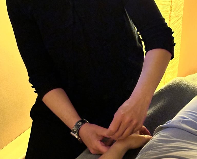 Acupuncturist inserting needle into patient’s wrist on acupuncture table. 