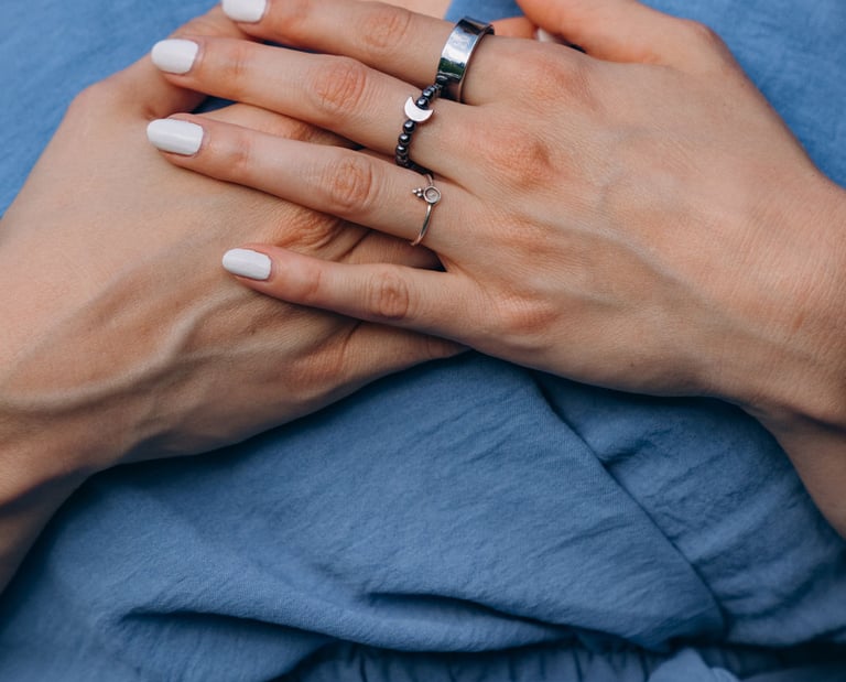 Woman with wearing silver moon and star rings over a blue wrap dress.
