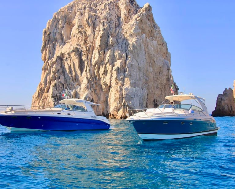 Luxury charter boats cruising near El Arco rock formation in Cabo San Lucas, Mexico.