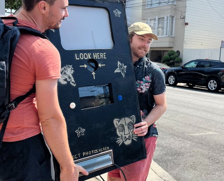 two men carrying a prototype photobooth made from wood