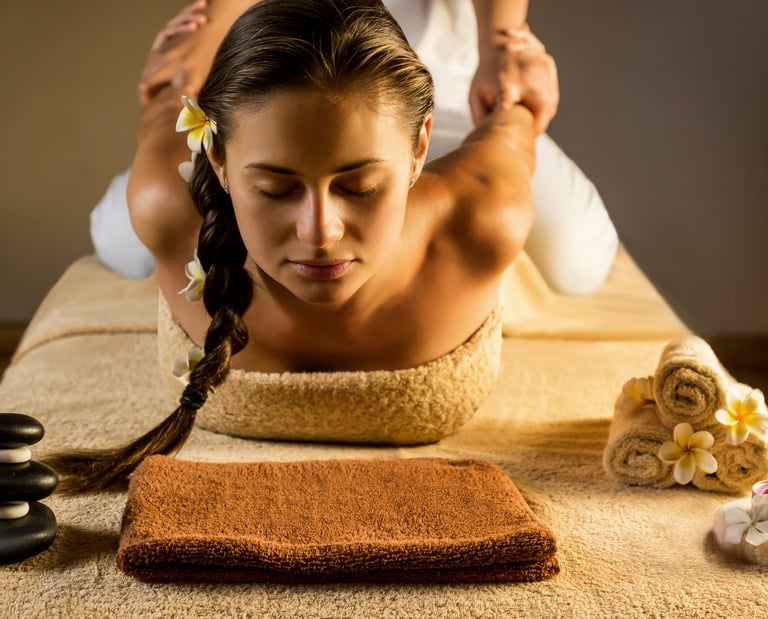 a long haired lady relaxes, eyes closed while the masseuse stretches and puls her 2 arms to her back