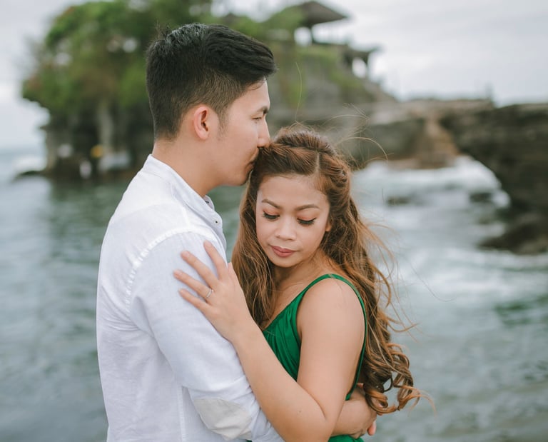 Intimate couple embrace with ocean backdrop at Tanah Lot Bali.