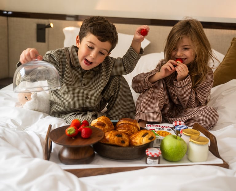 Enfants au petit déjeuner sur un lit de chambre d'hôtel