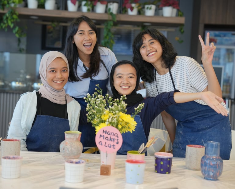 a group of women posing behind a table with flowers and handmade pots