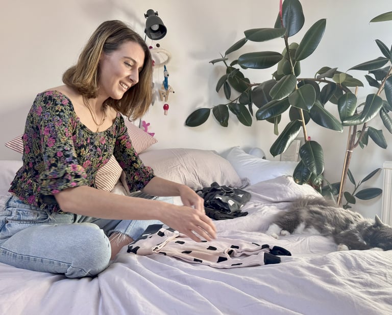 woman sitting on a bed folding clothes