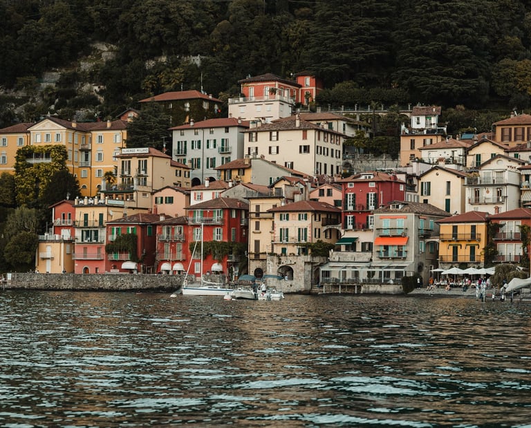 a bunch of houses on a hill with a boat in the water varenna lake como