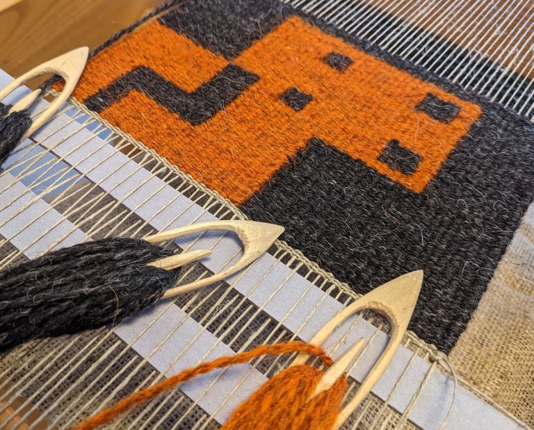 A weaving loom with shuttles and orange, yellow, and black wool threads on a kilim rug with a pixel-