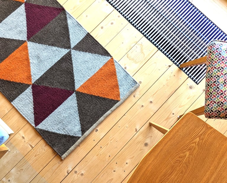 Modern handwoven kilim rug with geometric triangles in orange, burgundy and brown, adding warmth and