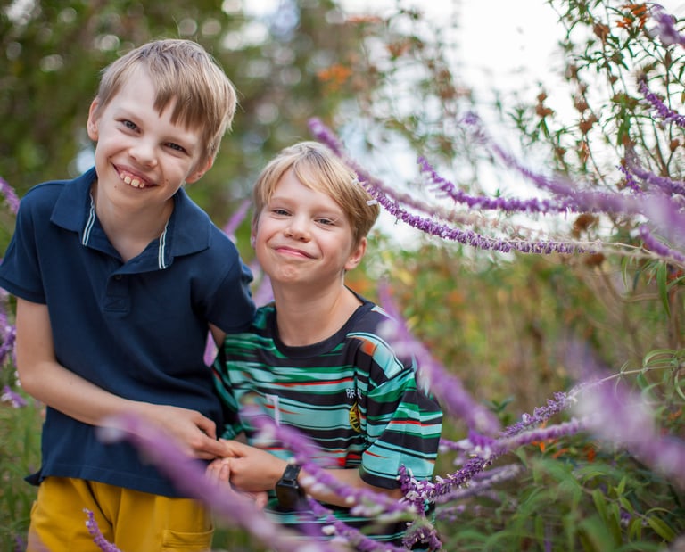 Two brothers share a happy moment surrounded by purple wildflowers in Pestana Grand, Madeira, natural lifestyle family photo.