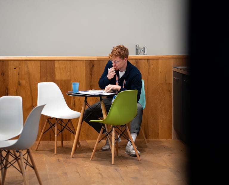 Journalist Przemysław "Przemek" Żuk sitzt an einem Tisch. Er denkt nach und schreibt handschriftliche Notizen.