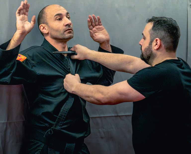 Self-defense instructor demonstrating a knife defense technique against a black belt martial artist.