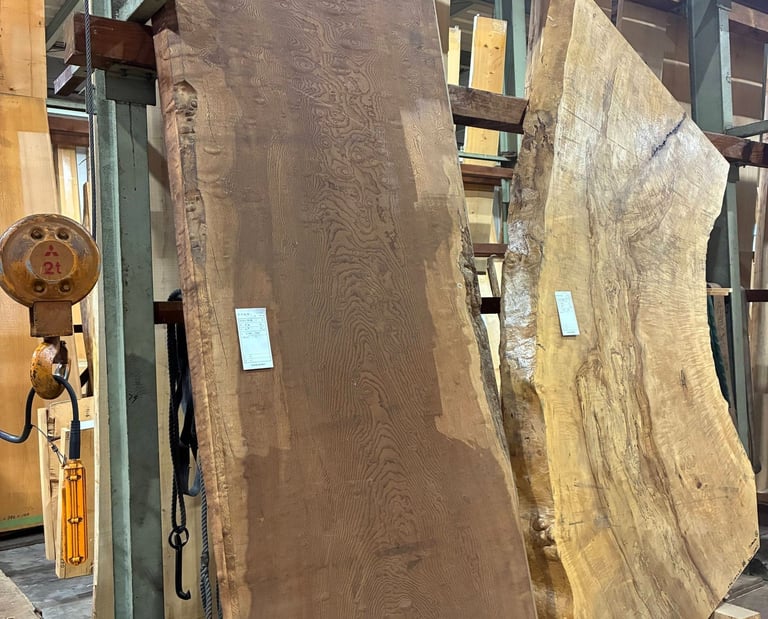 Large live edge wood slabs with natural grain patterns stored in a lumber warehouse in Japan.