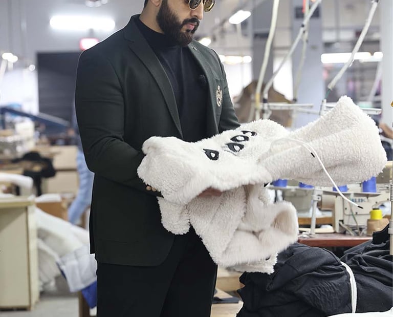 a man in a suit jacket is holding a sherpa fleece hoodie in a manufacturing  factory