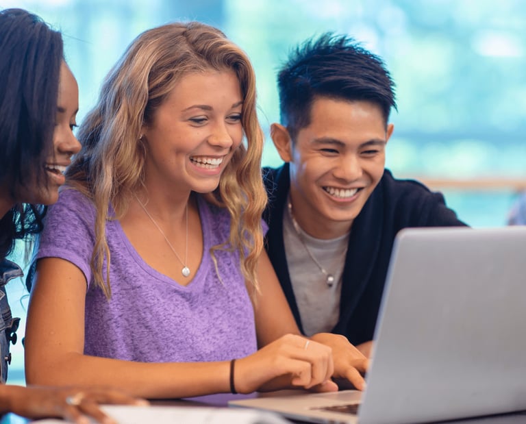 imagem de três jovens reunidos olhando para um computador estudando sobre finanças.