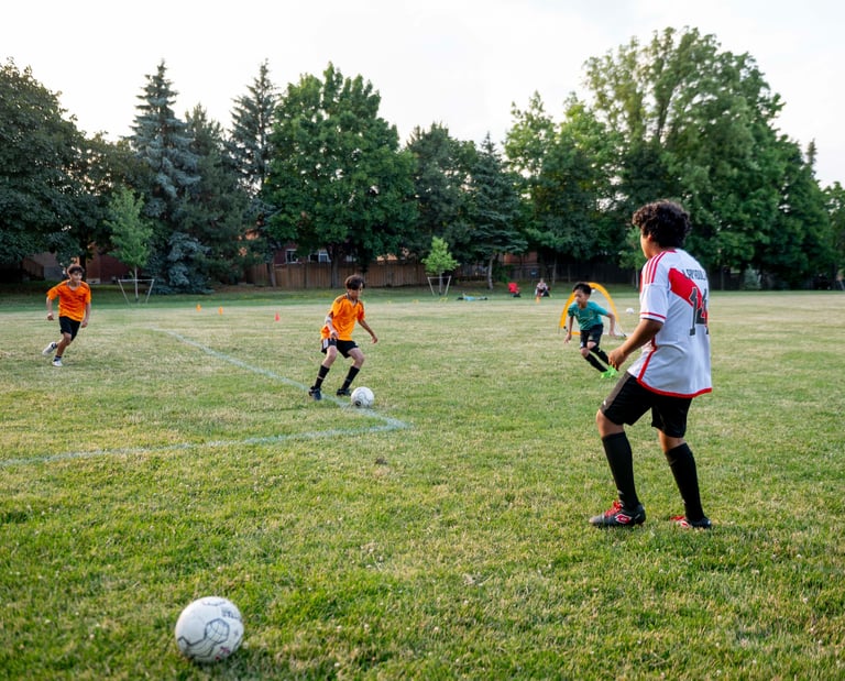 Young boys playing a soccer match on a grassy field during outdoor MVB FC soccer class Mississauga