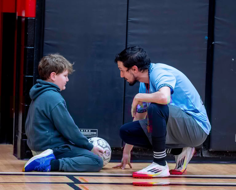 A soccer coach talking to a young boy at a soccer MVB FC class in Mississauga