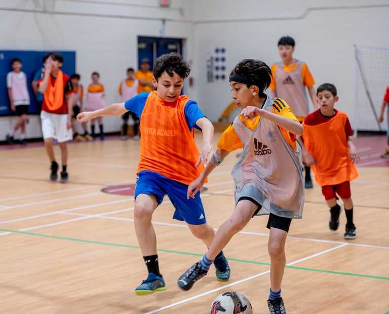 Youth players competing in an indoor soccer match during a MVB FC soccer class