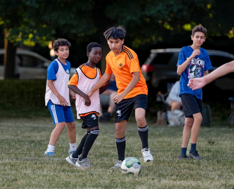 Youth soccer players MVB FC competing for a ball during a grass field match in Mississauga