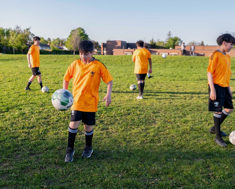 Youth soccer players MVB FC Soccer School practicing ball control drills on a green grass field
