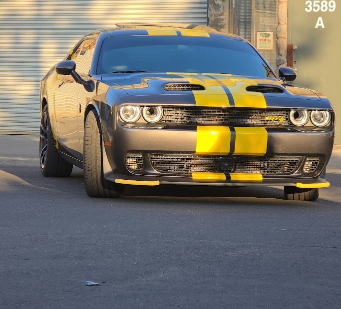 Custom automotive vinyl job: Yellow racing stripes applied from front to back on a black Dodge Chall