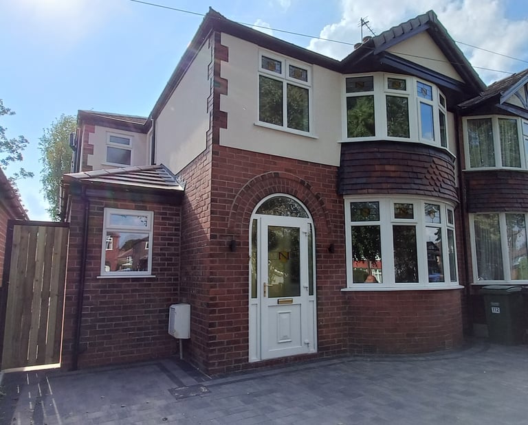 Modern semi-detached red brick house with white uPVC windows and a bay window on a paved driveway.