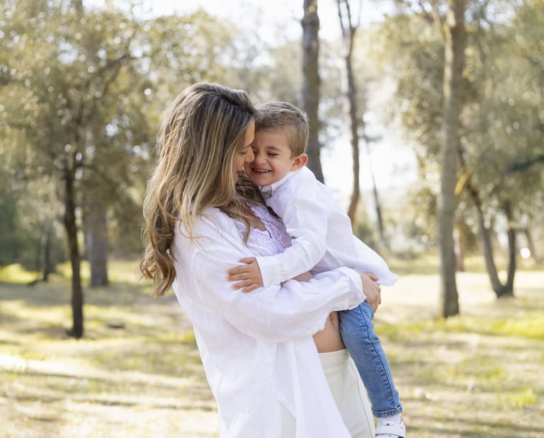 Sessió de fotos d'embaràs a Girona amb una dona embarassada abraçant fill un entorn natural exterior