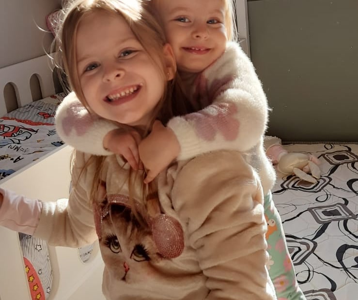 two young children in a bed with a teddy bear