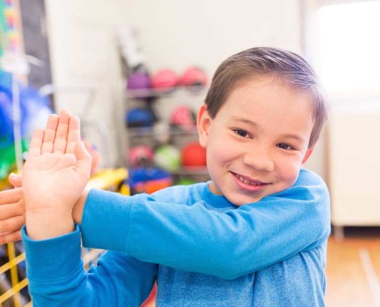 Elementary boy does a shoulder stretch.