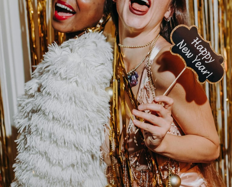 femmes souriantes portant des accessoires festifs dans une cabine photobooth, célébrant le Nouvel An