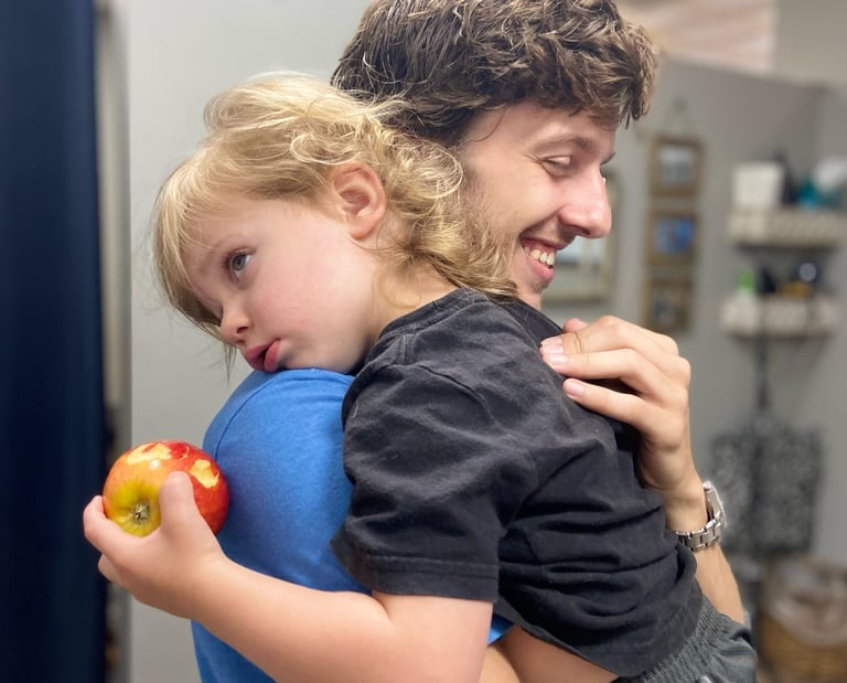 Child rests on Franklin Chiropractor's shoulder during adjustment to help him calm and rest