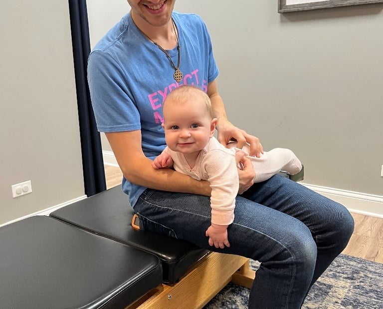 Joyful baby receiving gentle chiropractic care for sleep and digestion