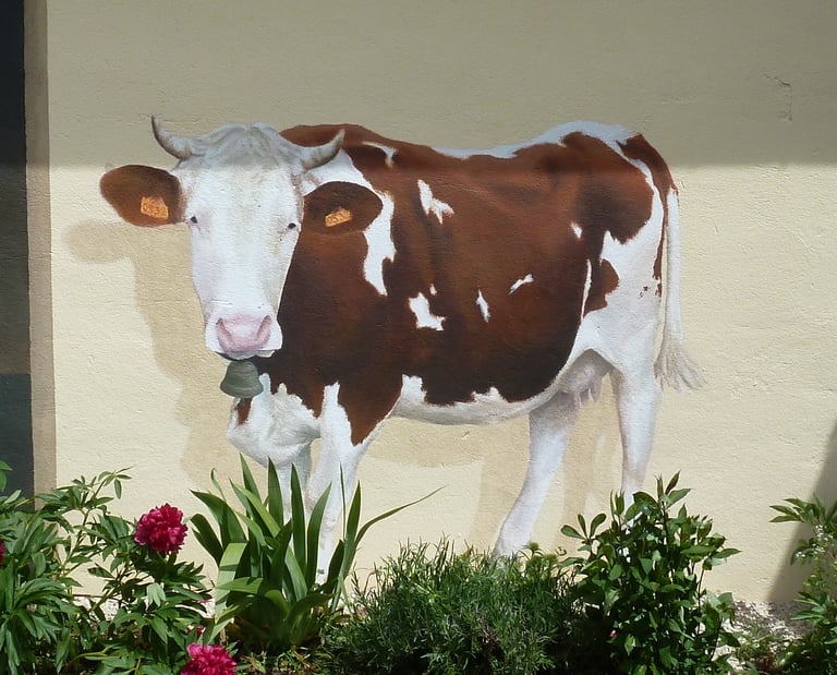 Détail d'un trompe-l'oeil sur façade: une vache Montbéliarde avec cornes et cloche. Echailla, Jura.