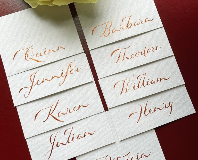 Beautiful calligraphy place cards in metallic bronze ink on white paper showcased on red background 